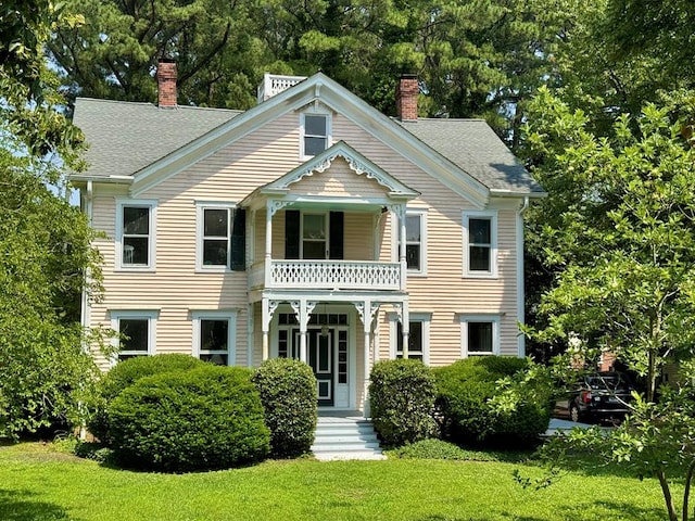 19 Cedardale Ln, Irvington, VA 22480 - view of front of home with a balcony, a chimney, a front yard, and roof with shingles