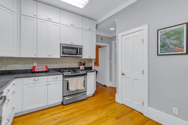 19 Cedardale Ln, Irvington, VA 22480 - kitchen with stainless steel appliances, dark countertops, decorative backsplash, light wood finished floors, and white cabinetry