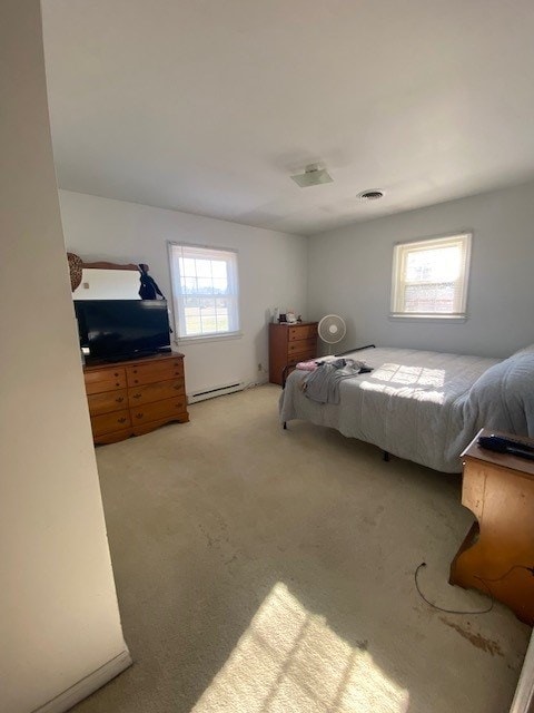 bedroom featuring a baseboard heating unit, light carpet, and visible vents