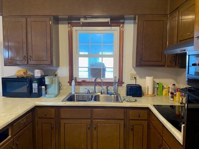 kitchen featuring light countertops, black appliances, a sink, and under cabinet range hood