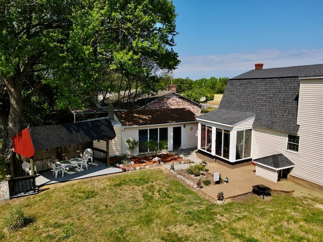 rear view of house featuring a wooden deck, a sunroom, and a yard