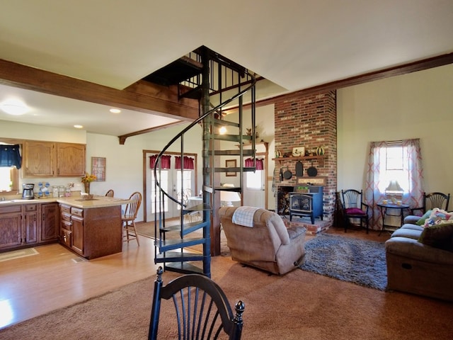 living room featuring beamed ceiling, light hardwood / wood-style floors, and a wood stove