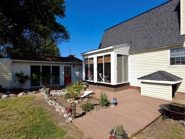 rear view of house with a wooden deck and a sunroom