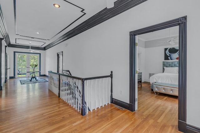 corridor with visible vents, baseboards, ornamental molding, an upstairs landing, and light wood-type flooring