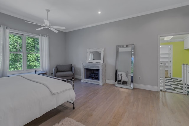 bedroom with baseboards, a fireplace, wood finished floors, and crown molding