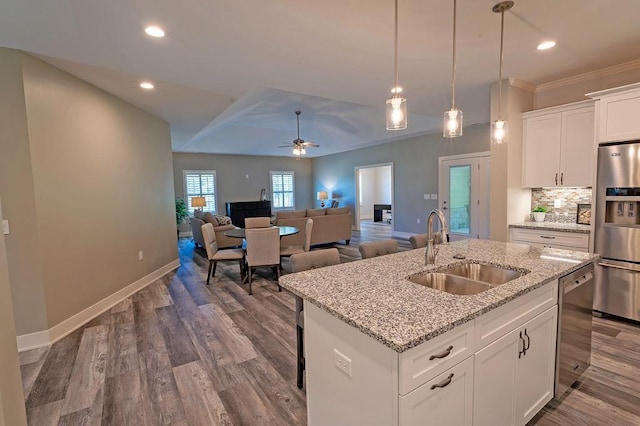 kitchen featuring an island with sink, ceiling fan, sink, decorative light fixtures, and white cabinetry