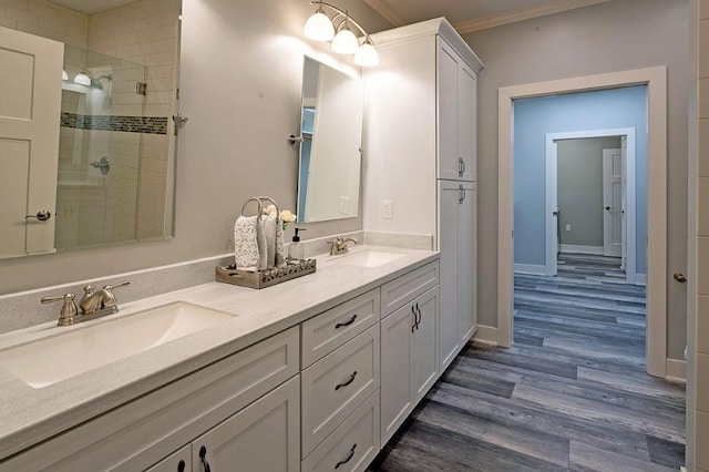 bathroom with walk in shower, vanity with extensive cabinet space, crown molding, dual sinks, and hardwood / wood-style flooring