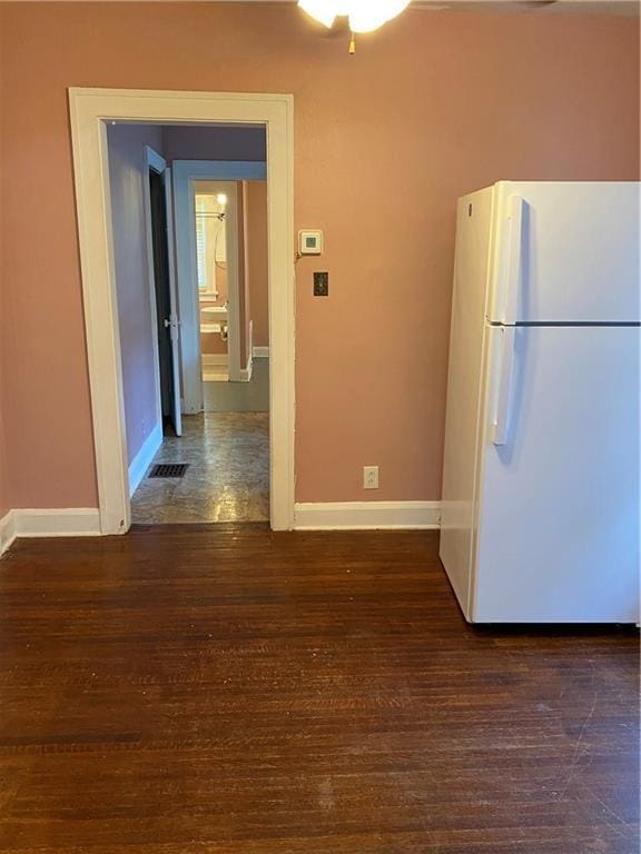 kitchen with dark tile flooring and white refrigerator