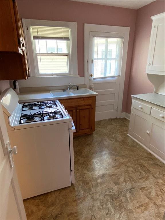 kitchen featuring sink, white range with gas cooktop, and light tile floors