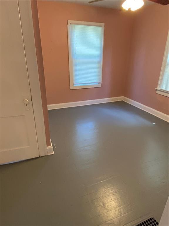 empty room featuring plenty of natural light, concrete floors, and ceiling fan