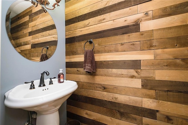 bathroom featuring wooden walls and sink