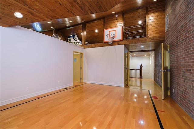 empty room with brick wall, wood ceiling, light hardwood / wood-style floors, and high vaulted ceiling