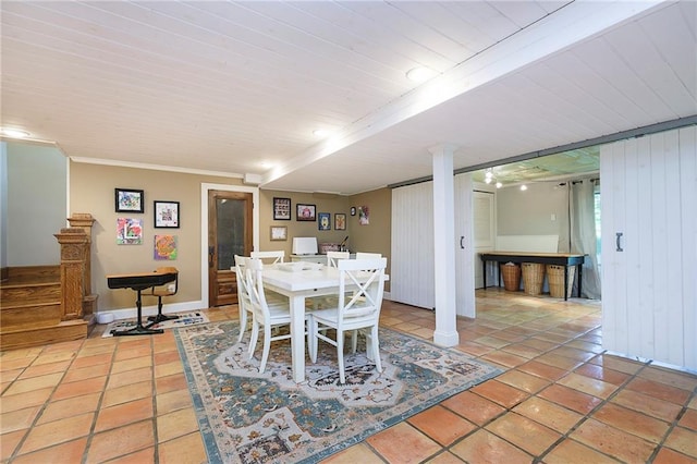 tiled dining room featuring wooden walls, ornamental molding, and ornate columns