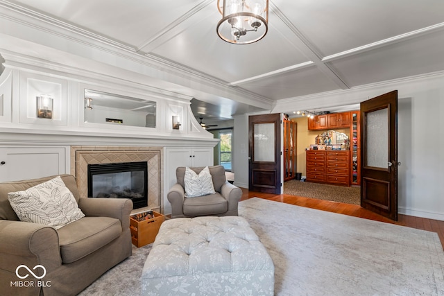 living room with ornamental molding, a fireplace, a chandelier, and dark hardwood / wood-style flooring