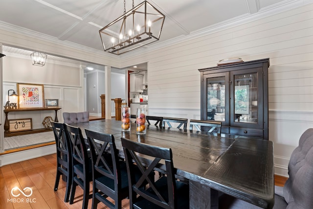 dining space with an inviting chandelier, hardwood / wood-style floors, and crown molding