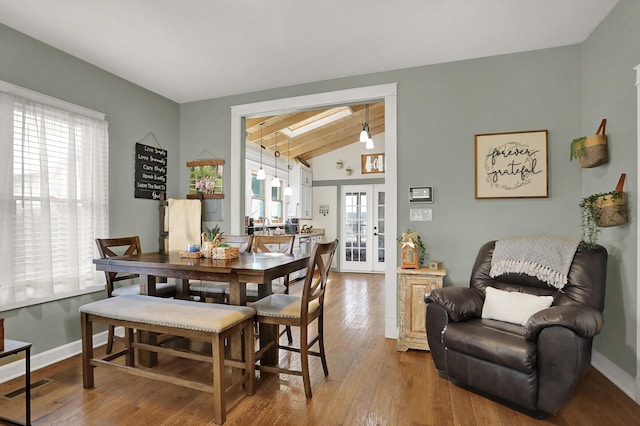 dining room with lofted ceiling with skylight, hardwood / wood-style floors, and french doors