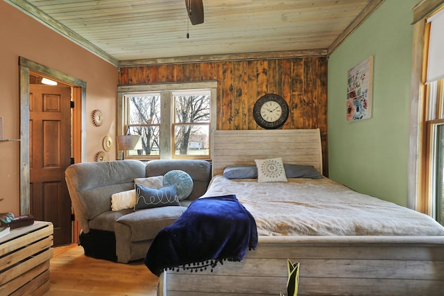 bedroom with wooden ceiling, wood walls, crown molding, light wood-type flooring, and ceiling fan