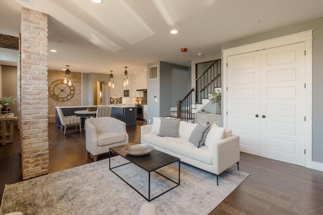 living room featuring brick wall and dark wood-type flooring