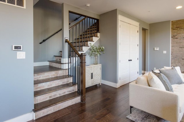 staircase with brick wall and dark hardwood / wood-style floors