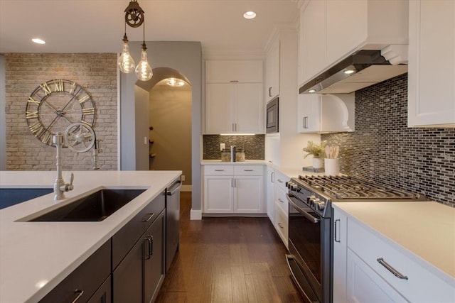 kitchen featuring white cabinets, pendant lighting, range with gas cooktop, backsplash, and sink