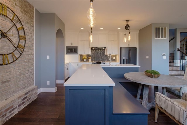 kitchen featuring decorative light fixtures, tasteful backsplash, an island with sink, and stainless steel appliances