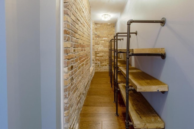 staircase with brick wall and dark hardwood / wood-style floors