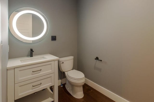 bathroom with toilet, vanity, and wood-type flooring