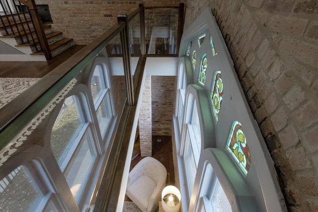 staircase featuring brick wall, hardwood / wood-style floors, and a high ceiling