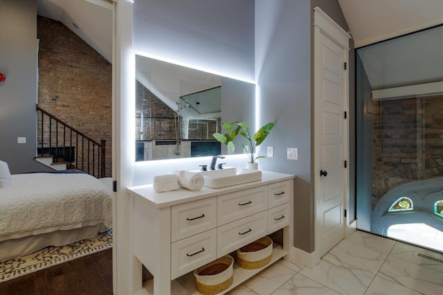 interior space featuring lofted ceiling, light hardwood / wood-style floors, brick wall, and sink