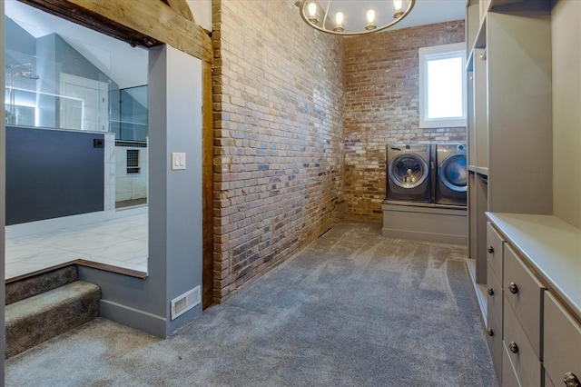 bathroom with washing machine and clothes dryer, brick wall, and a chandelier