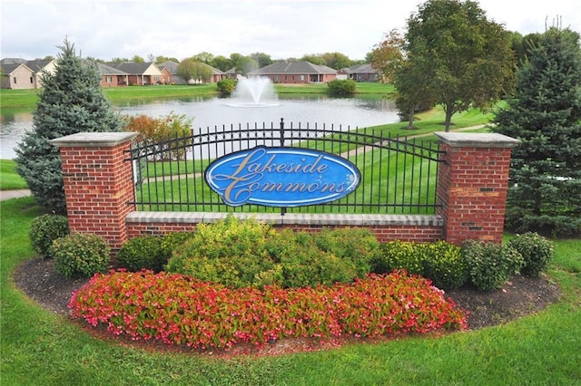 community sign featuring a lawn and a water view