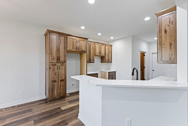 kitchen featuring kitchen peninsula, dark wood-type flooring, sink, and light stone countertops