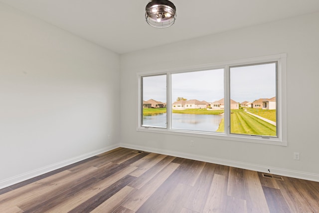 unfurnished room with dark hardwood / wood-style floors and a water view