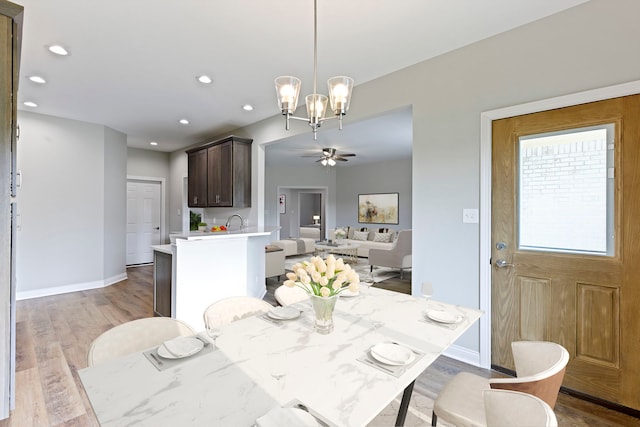 dining space featuring ceiling fan with notable chandelier and light hardwood / wood-style flooring