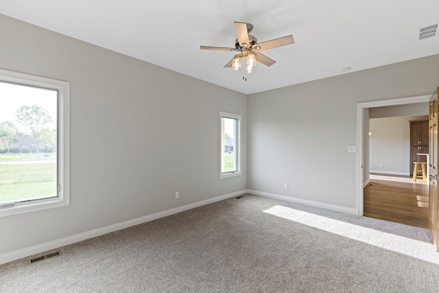 carpeted spare room with a healthy amount of sunlight and ceiling fan