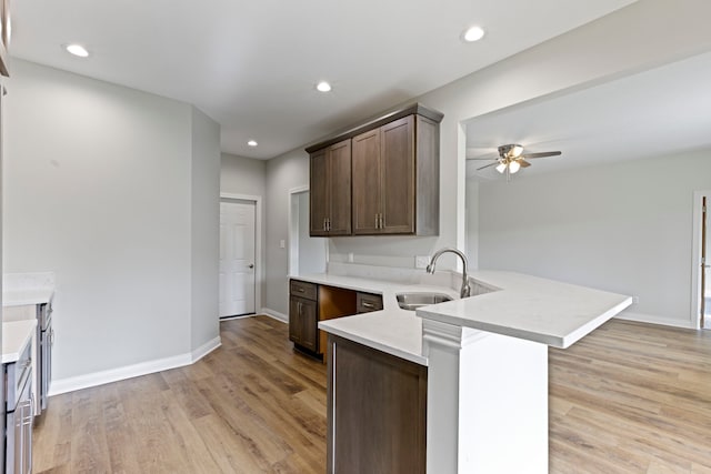 kitchen with sink, ceiling fan, light hardwood / wood-style floors, and kitchen peninsula