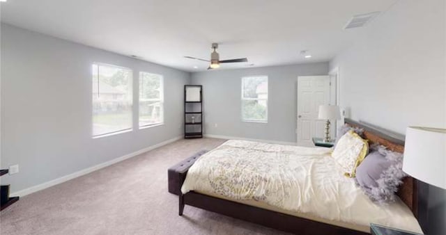 bedroom featuring light colored carpet, ceiling fan, and multiple windows