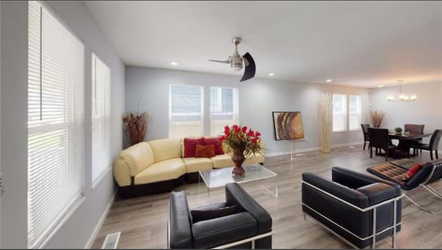 living room featuring light hardwood / wood-style floors and ceiling fan with notable chandelier