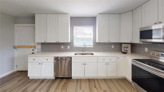 kitchen featuring appliances with stainless steel finishes, sink, white cabinetry, and light hardwood / wood-style floors