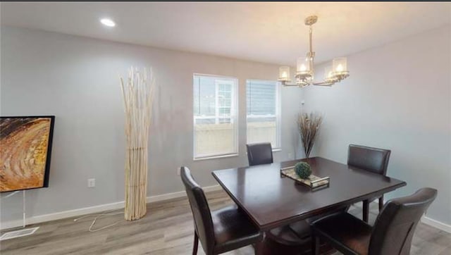 dining room with an inviting chandelier, a healthy amount of sunlight, and light hardwood / wood-style flooring