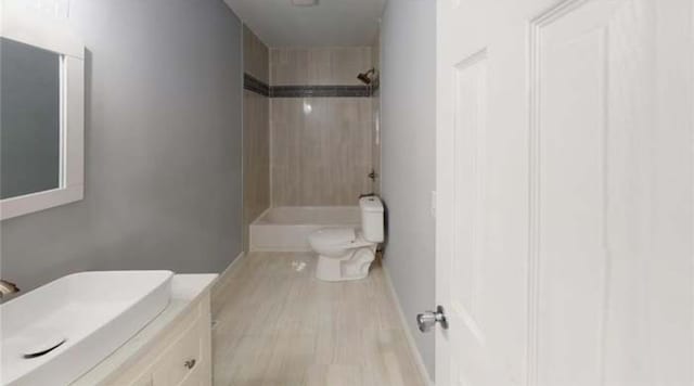 full bathroom with hardwood / wood-style floors, toilet, vanity, and tiled shower / bath