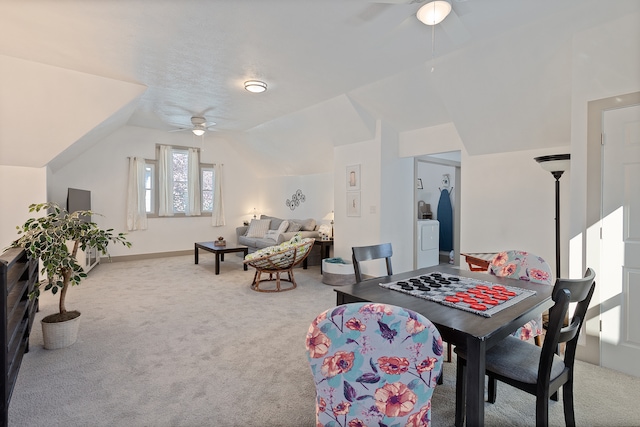 dining area featuring light colored carpet, vaulted ceiling, ceiling fan, and washer / dryer