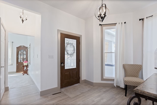 entryway featuring an inviting chandelier and light carpet