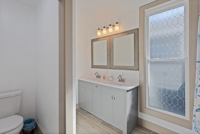 bathroom featuring dual vanity and toilet