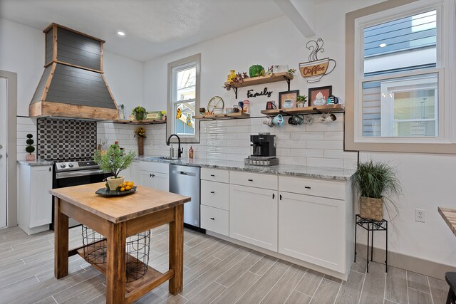 kitchen with tasteful backsplash, stainless steel appliances, white cabinets, and light stone counters