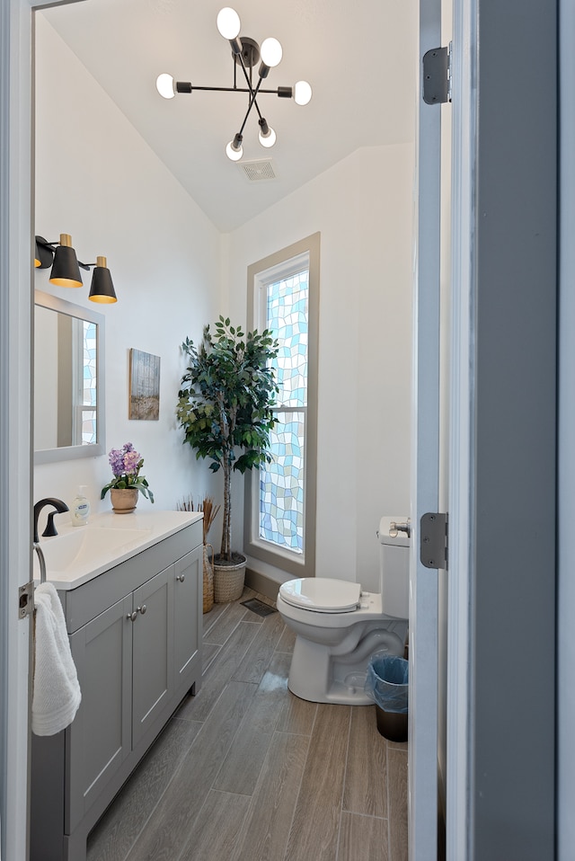 bathroom with hardwood / wood-style flooring, toilet, a chandelier, and vanity