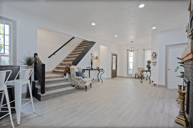 sitting room featuring light hardwood / wood-style flooring, an inviting chandelier, a fireplace, and a textured ceiling