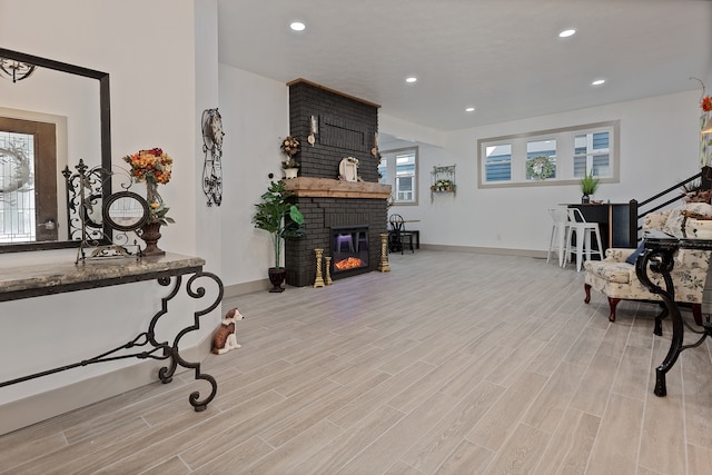 interior space featuring brick wall, light wood-type flooring, and a brick fireplace