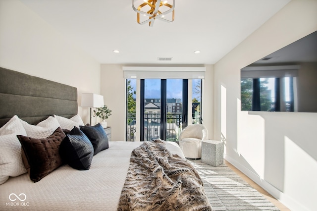 bedroom featuring an inviting chandelier, access to outside, and hardwood / wood-style flooring