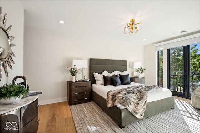 bedroom featuring access to exterior, a chandelier, and light hardwood / wood-style floors